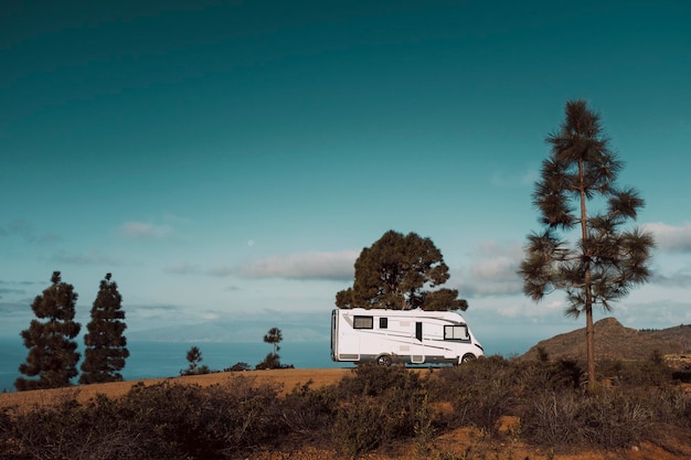 Camper moderno camper parcheggiato nella natura con vista cielo Concetto di persone e vacanza in veicolo di viaggio Avventura stile di vita vanlife e vita nomade Vacanze estive in campeggio