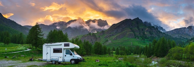 Camper nelle montagne delle Alpi Piemonte Italia Tramonto drammatico cielo e nuvole altopiani unici e montagne rocciose paesaggio alternativo concetto di vacanza vanlife