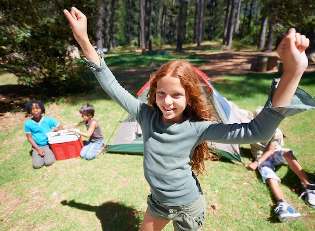 Camping eccitato o ritratto di ragazza in natura per giocare avventura o vacanze vacanze in parco Rilassarsi mani in alto o felice bambino giovane con sorriso in bosco giardino o foresta per giochi divertenti o infanzia