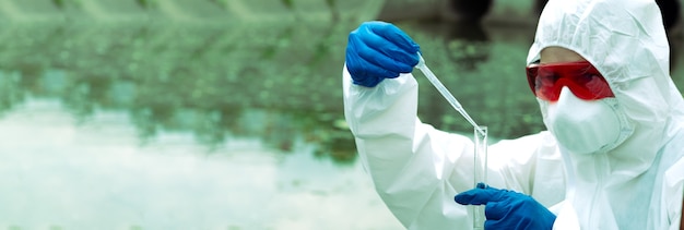 Campionamento in acque libere. Uno scienziato o un biologo preleva un campione d'acqua. Campione d'acqua in una provetta chimica con una pipetta.