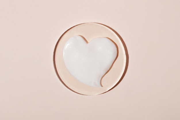 Campione di crema cosmetica a forma di cuore. Sfondo pastello, buono come mockup.