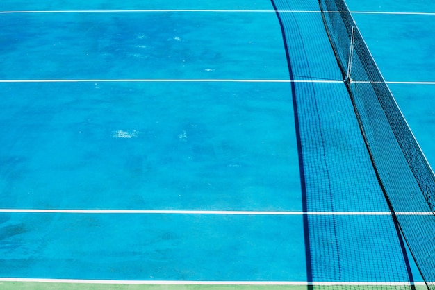 Campo da tennis deserto con alberi verdi sullo sfondo in un parco pubblico in una soleggiata mattina d'estate