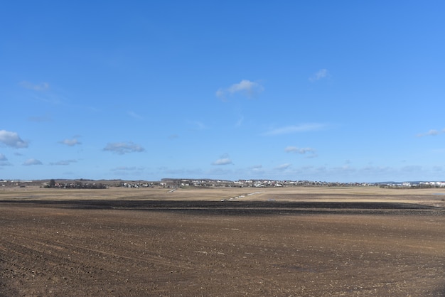 Campo di fattoria di primavera senza vegetazione vicino al villaggio