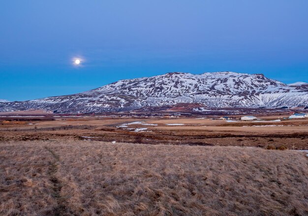 Campo di montagna nel cielo serale crepuscolare con luce notturna di luna piena nella stagione invernale in Islanda