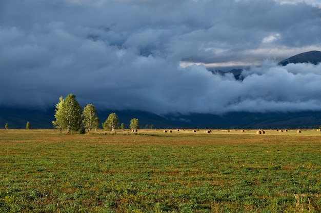 Campo, montagne e nuvole. Panorama serale dopo la pioggia.