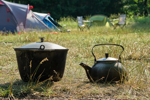 Campo turistico Un bollitore e una pentola da cucina turistica Tende da campeggio e sedie pieghevoli sullo sfondo