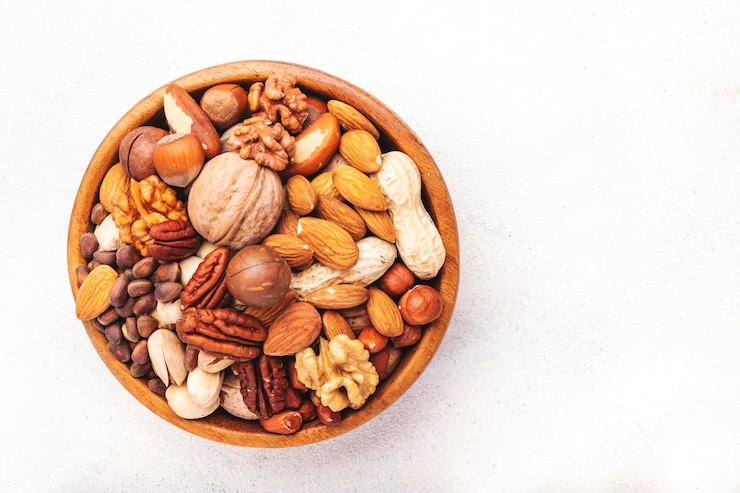 Photo campuran kacang dalam mangkuk almond, hazelnut, walnut, dan lainnya camilan makanan sehat campuran di atas meja putih tampilan atas ruang salin