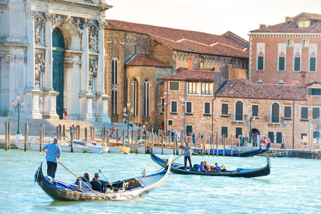 Canal Grande con gondole, turisti e Basilica di Santa Maria della Salute in una giornata di sole. Venezia, Italia