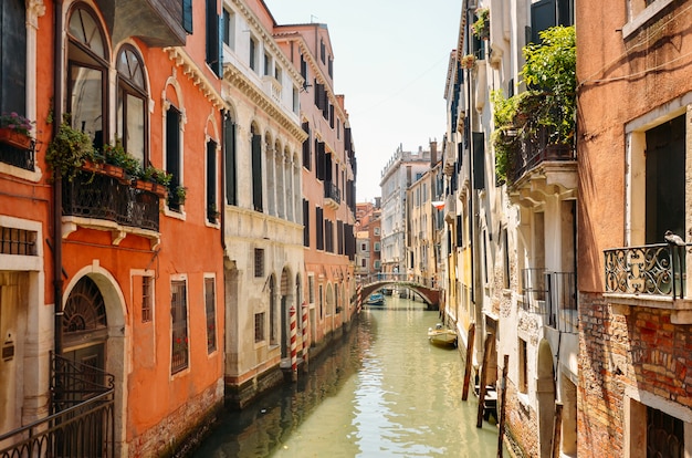 Canale stretto con la barca e ponte a Venezia, Italia. Architettura e punto di riferimento di Venezia. Accogliente paesaggio urbano di Venezia