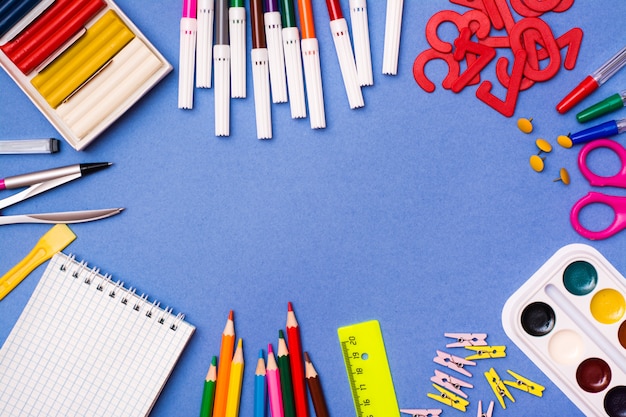 Cancelleria, oggetti per il disegno e la creatività sono disposti in una cornice su un blu