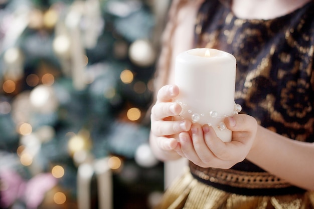 Candela accesa nelle mani di una ragazza. Candela di Natale. Decorazioni natalizie. Mani del bambino che tengono bella candela con il fuoco