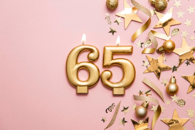 Candela di celebrazione dell'oro numero 65 su sfondo stellato e glitter