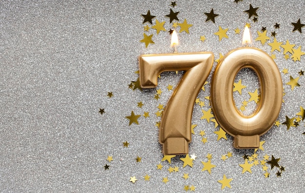 Candela di celebrazione dell'oro numero 70 su sfondo stellato e glitter