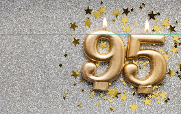 Candela di celebrazione dell'oro numero 95 su sfondo stellato e glitter