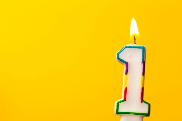 Candela di celebrazione di compleanno numero 1 su uno sfondo giallo brillante