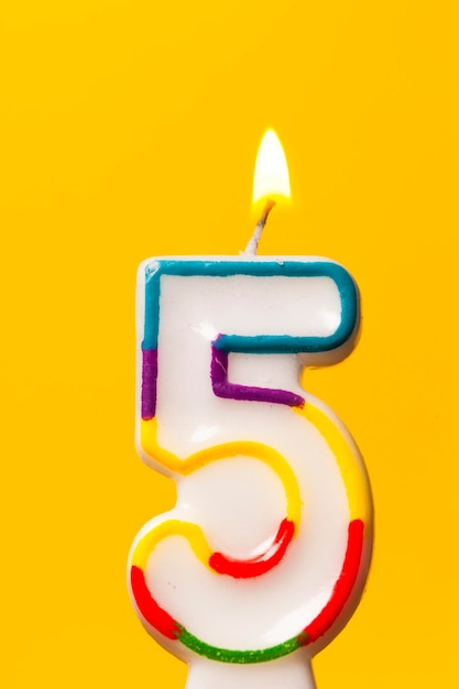 Candela di celebrazione di compleanno numero 5 su uno sfondo giallo brillante