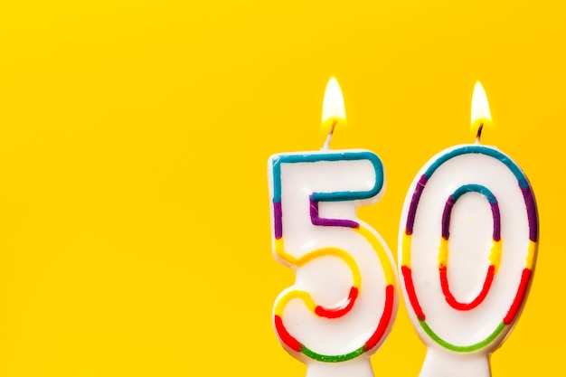 Candela di celebrazione di compleanno numero 50 su uno sfondo giallo brillante