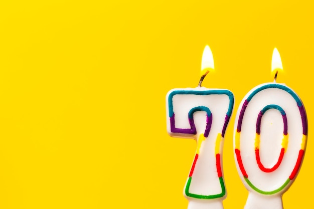 Candela di celebrazione di compleanno numero 70 su uno sfondo giallo brillante