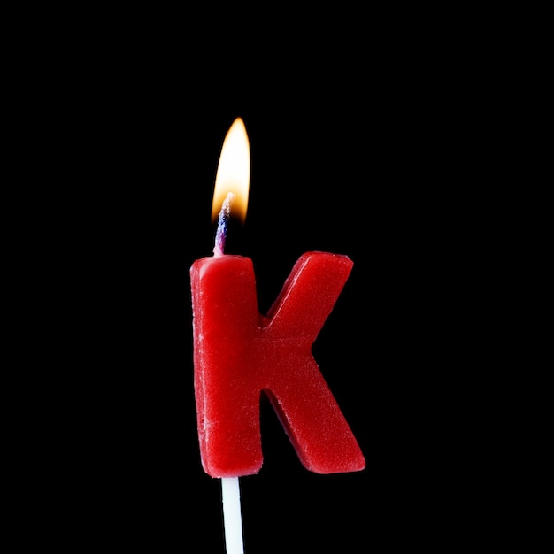 Candela di compleanno di celebrazione della lettera K su uno sfondo nero