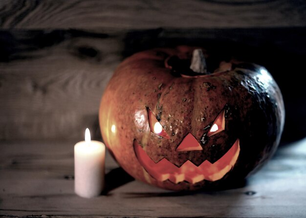 Candela e una zucca di Halloween sorridente inquietante su un tavolo di legno.foto con spazio di copia