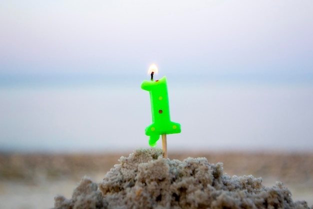 Candela numero uno sul bastone inserito nella sabbia e brucia una candela accesa