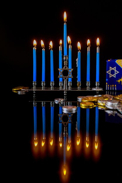 Candele accese blu sulla menorah con monete di cioccolato per la festa ebraica di Hanukkah.