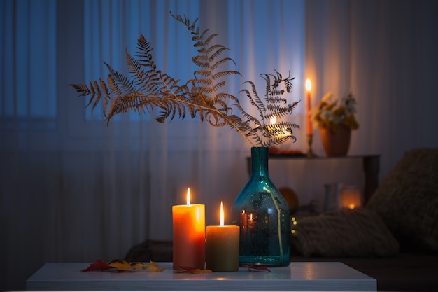 candele accese con decorazioni autunnali sul tavolo bianco a casa