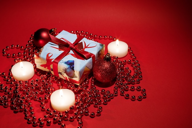 Candele accese con un regalo di Natale su sfondo rosso. spazio libero per il testo. Biglietto natalizio