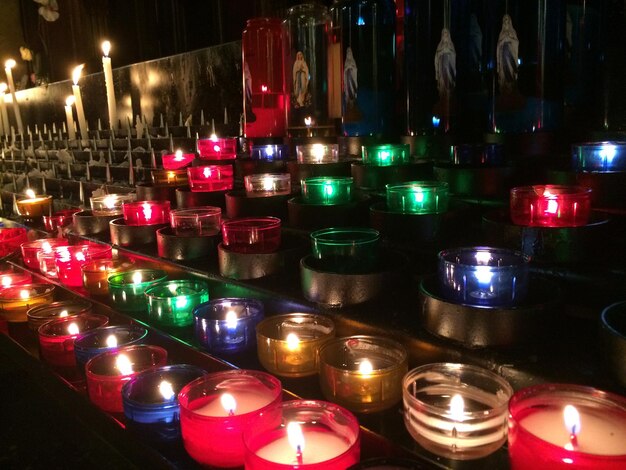 Candele al tè multicolori accese in chiesa di notte