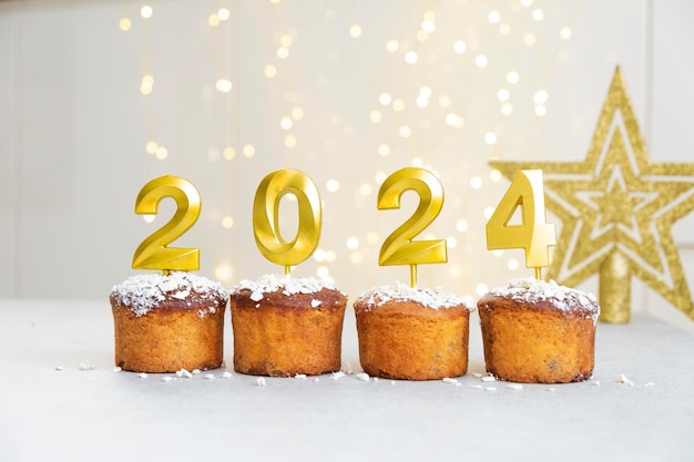 Candele d'oro con il numero 2024 in cima ai cupcake Buon Natale e Buon Anno Nuovo