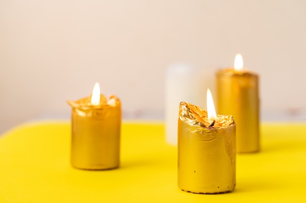 Candele d'oro su sfondo giallo. Wellnes, magia, concetto di relax. Casa accogliente. Copia spazio