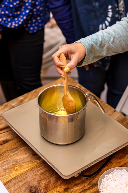 Candele di cera di soia Giovane donna con unghie dipinte di giallo sta bollendo la cera per scioglierla