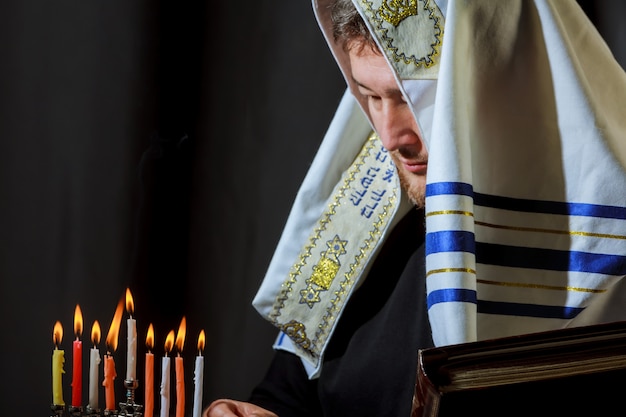 Candele di illuminazione della mano maschio in menorah sul tavolo Hanukkah