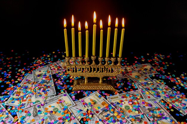 Candele dorate su menorah e coriandoli con soldi sulla superficie nera. Simbolo della festa ebraica di Hanukkah.