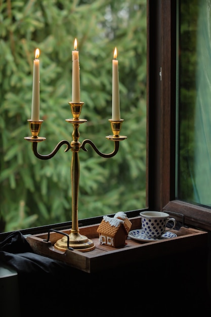 Candele e tazza di caffè con biscotti di pan di zenzero in vassoio e finestra