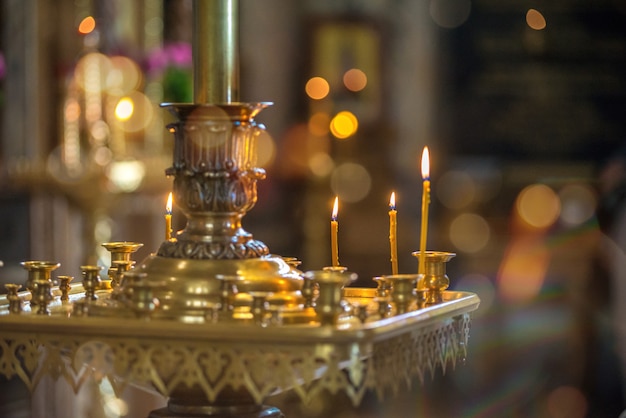 Candele gialle accese nella Chiesa, in piedi su un piedistallo.