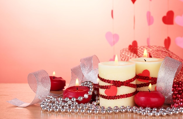 Candele per San Valentino su tavola di legno su sfondo rosso