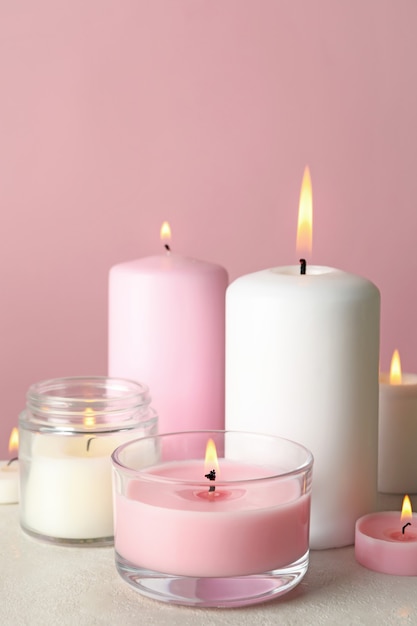 Candele profumate per il relax sul tavolo bianco contro la superficie rosa