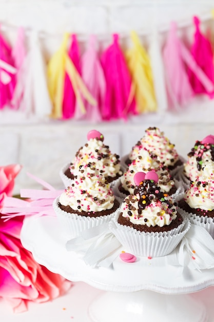 Candy bar di compleanno Cupcakes al cioccolato con crema al formaggio e decorazioni multicolori