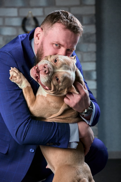 Cane bulli e il suo padrone, il suo amorevole padrone che tiene il cane tra le braccia, abbracci e baci. Il cane si sente bene nelle mani del proprietario