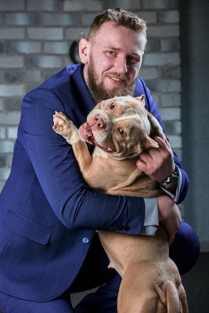 Cane bulli e il suo padrone, il suo amorevole padrone che tiene il cane tra le braccia, abbracci e baci. Il cane si sente bene nelle mani del proprietario