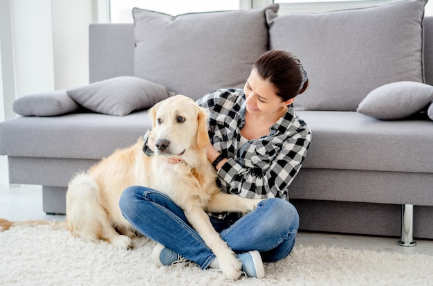 Cane carino petting donna felice in appartamento luminoso