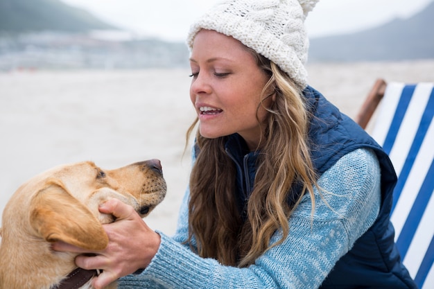 Cane di coccole della donna mentre sedendosi sulla sedia