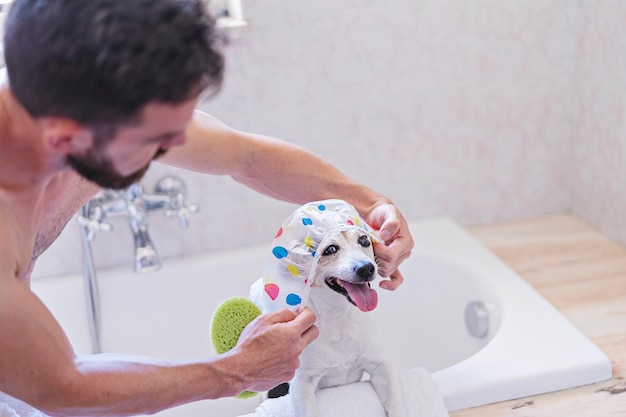 Cane divertente con cuffia per la doccia che si diverte con le bolle di sapone in bagno con il proprietario