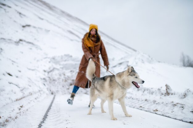 Cane husky e donna in montagna nevosa di inverno