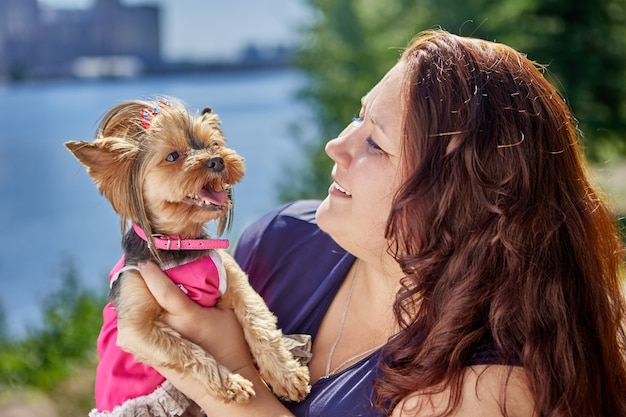 Cane yorkshire terrier tra le braccia di una donna caucasica matura e spessa