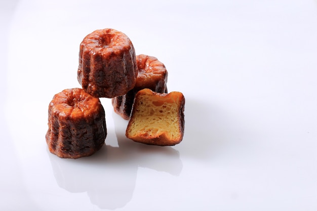 Canele o Cannele, pasticceria francese di Bordeaux. Aromi Rum e Vaniglia con un centro di crema pasticcera tenera e una spessa crosta caramellata. Isolato su sfondo bianco, messa a fuoco selettiva