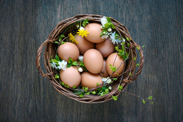 Canestro della primavera delle uova naturali di pasqua sulla parete di legno, vista superiore.