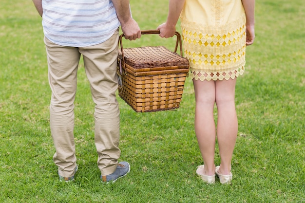 Canestro di picnic felice della tenuta delle coppie fuori