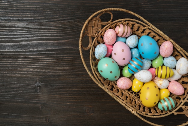 Canestro in pieno delle uova di Pasqua variopinte su fondo di legno. Buona Pasqua